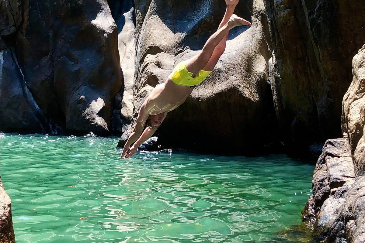 Tourist jumping into freshwater pool at Ba Ho Waterfall