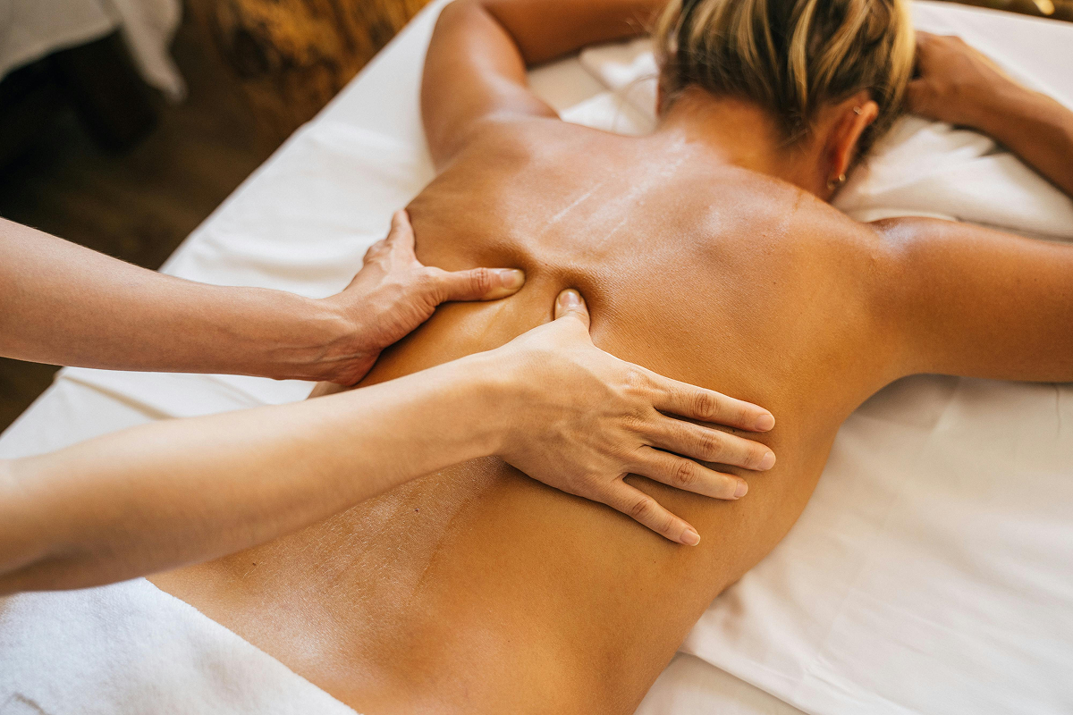 Therapist performing full body massage at spa